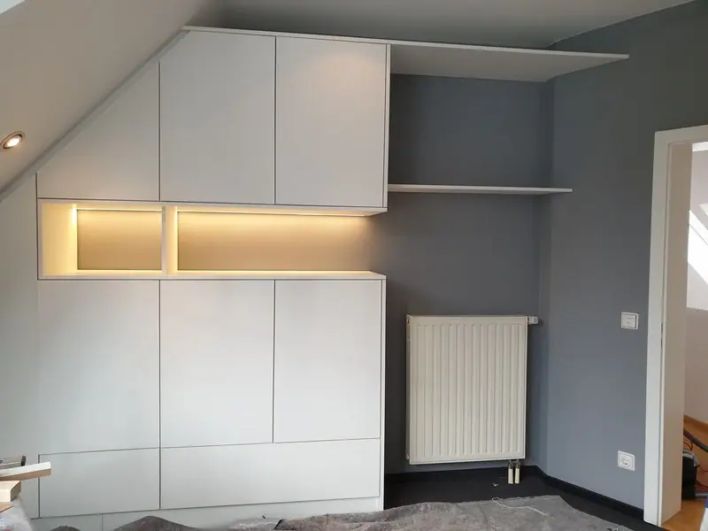 Dunkelgraue Einbauschrankwand unter einer Dachschräge, mit Schubladen und Fächern