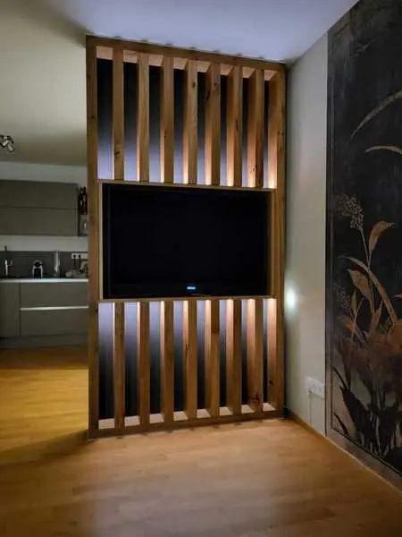 Wand mit senkrechten Holzlamellen und Hinterleuchtung um einen Fernseher